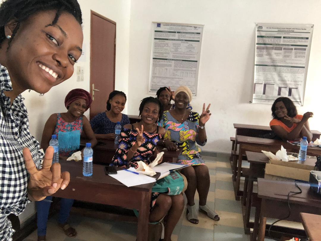 Happy members of R-Ladies Cotonou gathered around a table with pastries