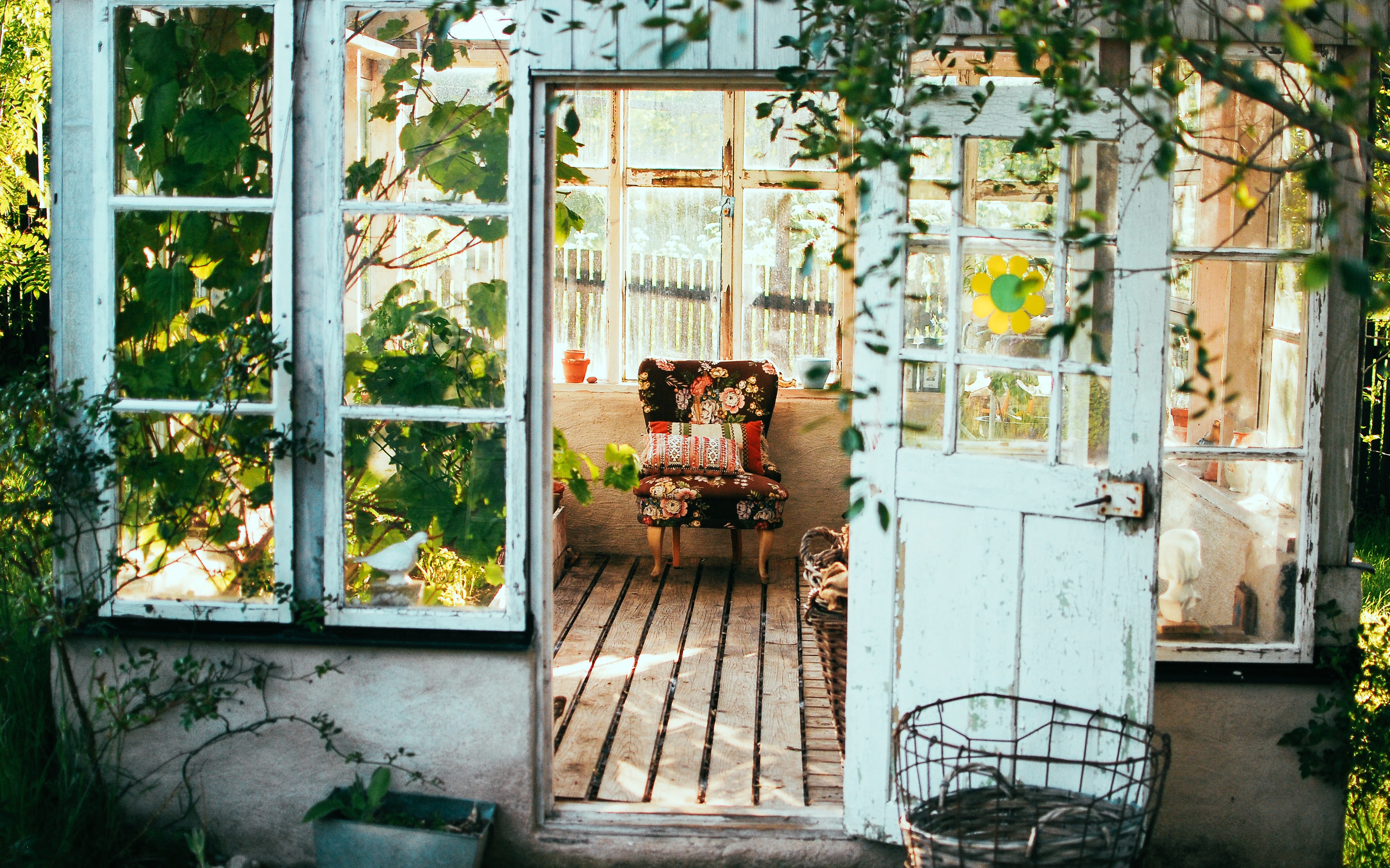 Open door leading to a porch with an inviting sitting chair, surrounded by plants
