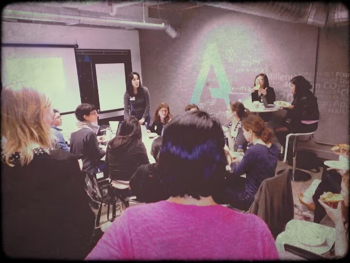 An early RLadies+ San Francisco meetup in January 2014, with members gathered around a table for a presentation