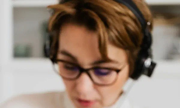 Condenser microphone in the foreground with a woman reading in the background
