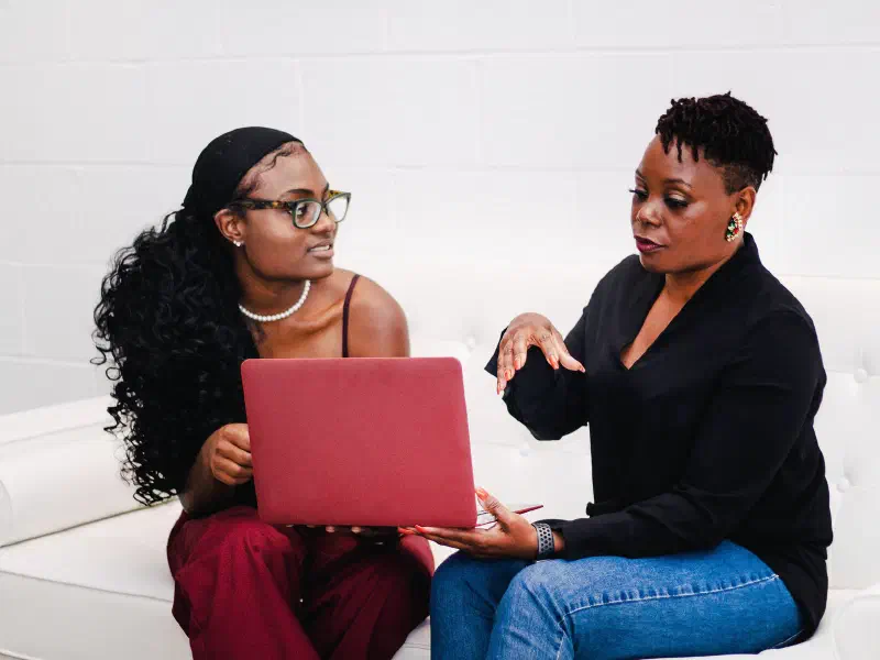 Two women of color discussing work together
